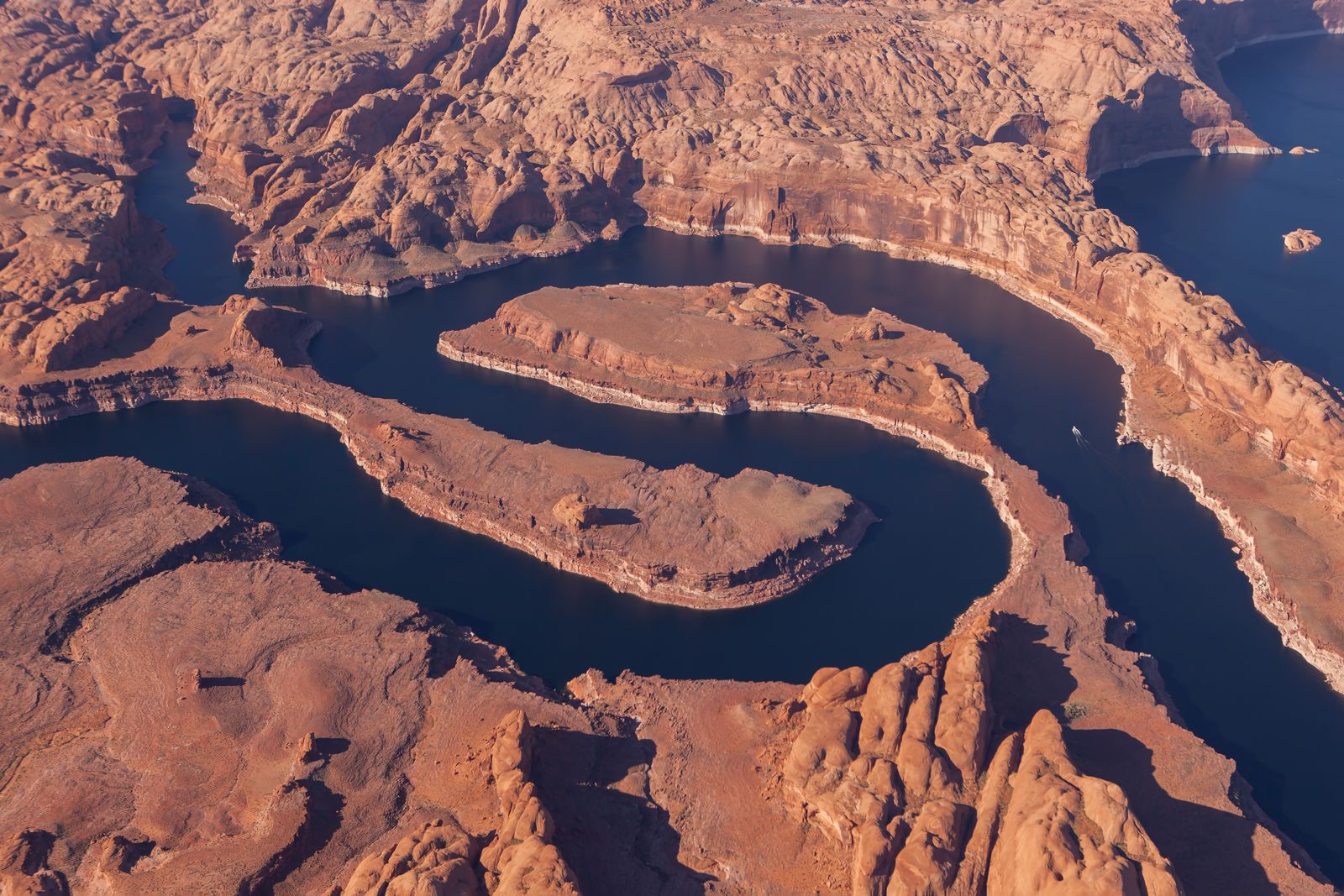 Aerial view of Lake Powell's dark blue water winding between red rock